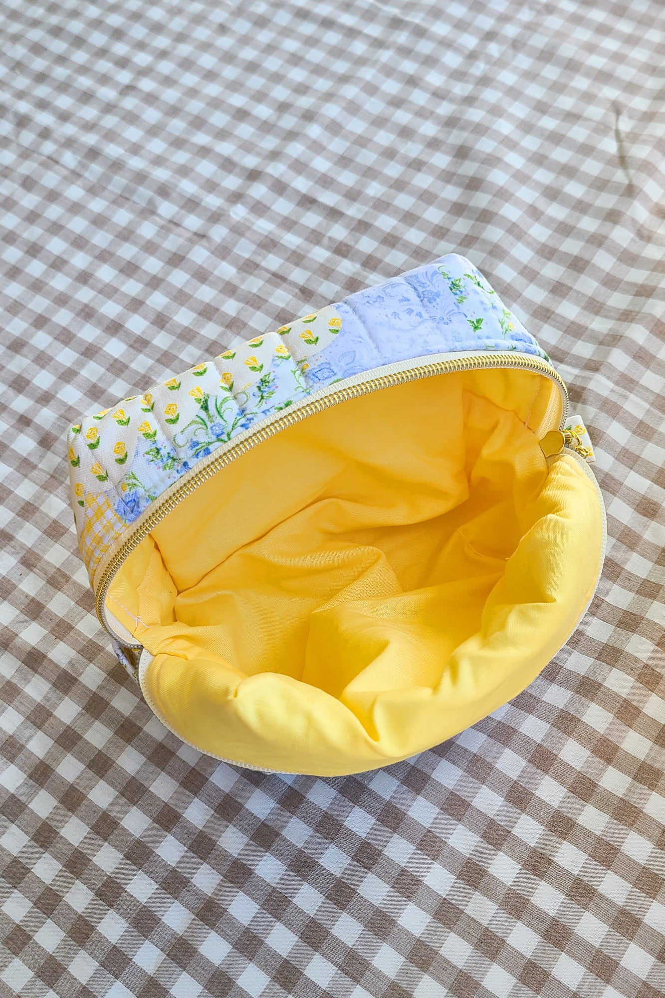 Small pouch with floral top section and yellow interior on a checkered fabric background