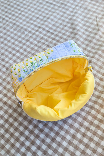 Small pouch with floral top section and yellow interior on a checkered fabric background