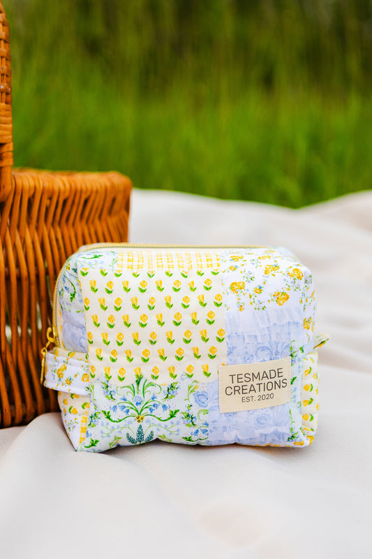 Fabric pouch with floral pattern and 'Tesmade Creations' label on a white surface with green grass in the background.