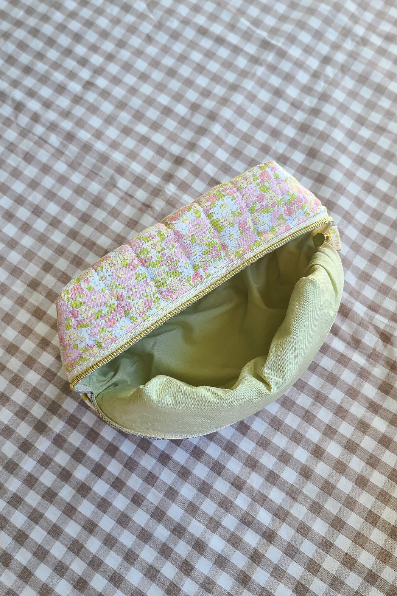 Floral-patterned zippered pouch on a checkered fabric background