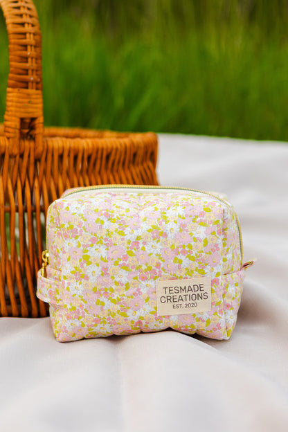 Floral-patterned pouch with 'Tesmade Creations' label on a white surface with a wicker basket in the background.