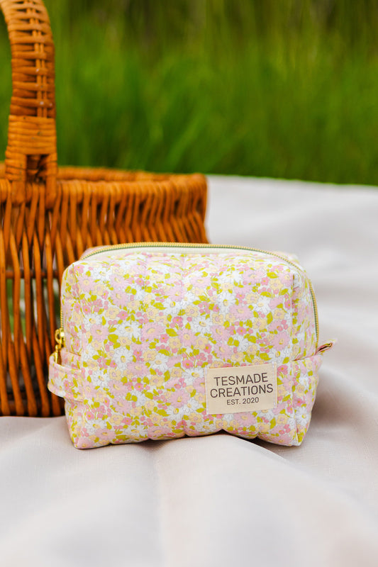 Floral-patterned pouch with 'Tesmade Creations' label on a white surface with a wicker basket in the background.