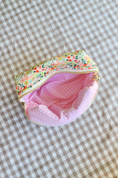 Floral-patterned fabric pouch with pink interior on a checkered background